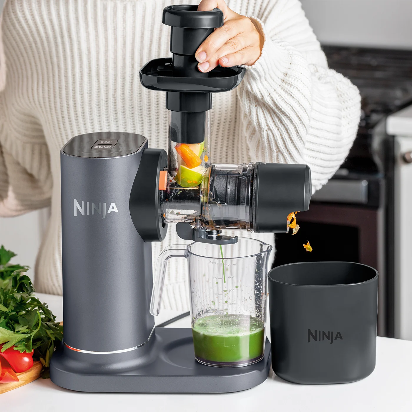 Ninja-JC151UK-InUse-OnIsland-FillFunnel-Dispense-Pulp-Woman_rlpwvj